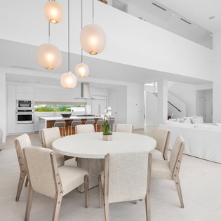 Relax in your stunning open-plan living space with soaring ceilings, elegant pendant lighting, and seamless flow between dining and kitchen areas.