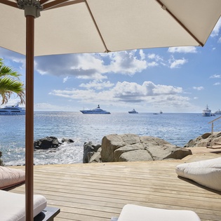 Unwind on your private deck overlooking crystal-blue waters, where luxury yachts drift by and gentle waves kiss the rocks below.