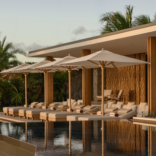 Luxury poolside pavilion with elegant daybeds and umbrellas creates the perfect tropical retreat for relaxation and sophisticated leisure.