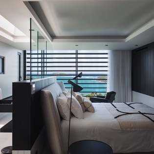 Wake up to stunning ocean views through floor-to-ceiling windows in your modern bedroom sanctuary with sleek design and luxurious comfort.