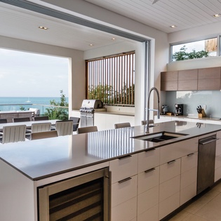 Cook with stunning sea views in this modern kitchen with sleek island and outdoor dining space.