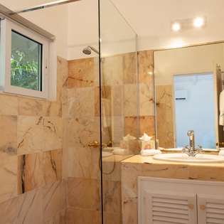 Indulge in marble luxury with your walk-in shower and elegant vanity, complete with tropical garden views through frosted windows.