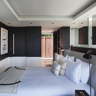 Relax in your sleek modern bedroom with crisp white linens and sophisticated dark wood accents creating a serene retreat.