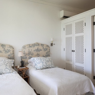 Two plush twin beds with charming toile headboards invite peaceful rest, while your private en-suite bathroom awaits just beyond the latticed closet doors.