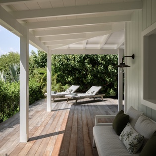 Relax on your private covered terrace with tropical garden views, where soft cushions and wooden loungers await your peaceful moments.