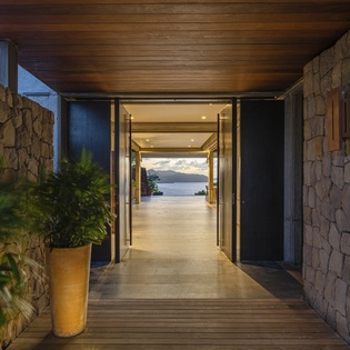Modern stone entrance creates a stunning first impression with dramatic ocean views beckoning beyond sleek architectural lines.