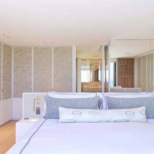 Drift into peaceful sleep in your serene modern bedroom with stylish glass partitions and luxurious linens.