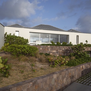 Modern architectural design featuring stone landscaping and natural vegetation creates an impressive arrival experience.