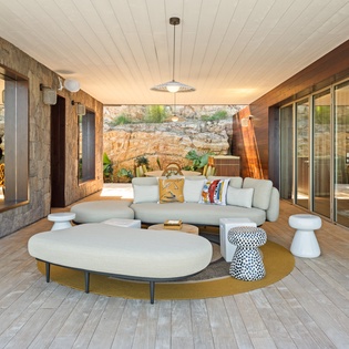 Sink into plush seating in your covered outdoor living space, where natural stone walls and modern comfort create the perfect retreat.
