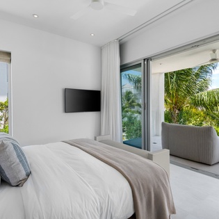 Wake up to lush tropical views from your serene bedroom suite, where floor-to-ceiling windows frame swaying palms and your private balcony beckons.