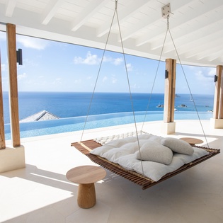 Drift away on your private hanging daybed while gazing at endless ocean views through floor-to-ceiling windows.