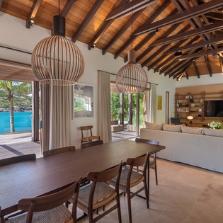 Unwind in your stunning open-plan living space where warm wood beams frame breathtaking ocean views and modern comfort meets tropical elegance.