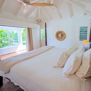 Wake to lush tropical views from your elegant four-poster bed. The vaulted ceiling and ceiling fan keep you cool while natural light fills your serene island retreat.