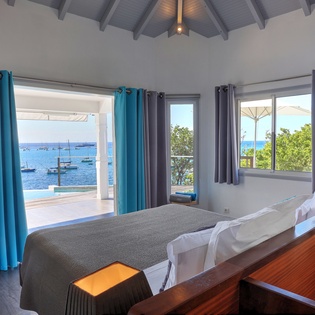 Wake up to stunning ocean views from your comfortable bed, with boats dotting the sparkling blue waters beyond your private terrace.