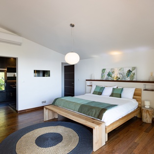 Your tranquil master bedroom features warm wood floors, modern furnishings, and natural light streaming through large windows creating a peaceful retreat.