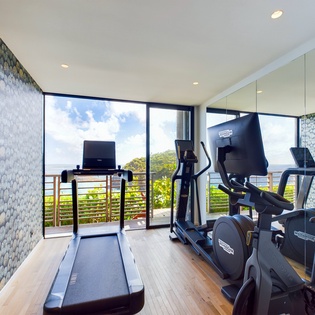 Your workouts get a stunning upgrade with floor-to-ceiling windows framing tropical views, modern equipment, and beautiful stone accent walls.