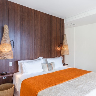 Sink into crisp white linens beneath warm pendant lights, where the rich wood accent wall creates a cozy retreat for your perfect night's rest.