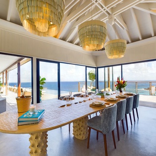 Enjoy ocean views from your elegant dining space, where golden chandeliers create perfect ambiance for memorable meals with panoramic sea vistas.