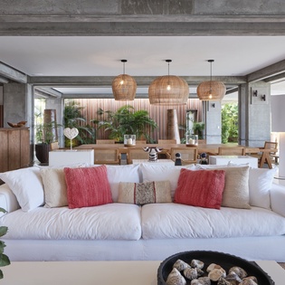 Sink into plush white sofas surrounded by natural textures and warm lighting in this open living space.