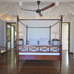 Drift off beneath soaring cathedral ceilings and gentle ceiling fan breezes in your elegant four-poster bed sanctuary.