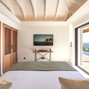 Step into your serene living space where warm wood meets stunning ocean views through floor-to-ceiling windows.