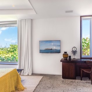 Your bedroom workspace overlooks lush tropical greenery through floor-to-ceiling windows, creating a serene sanctuary for both rest and productivity.