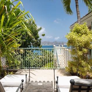 Stretch out on your private loungers and soak in the sparkling blue ocean views framed by lush tropical palms and elegant garden landscaping.