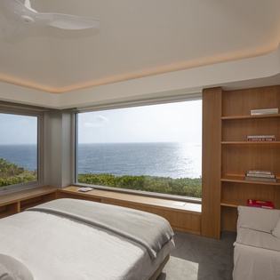 Wake up to stunning ocean views from your private sanctuary with floor-to-ceiling windows and built-in shelving.
