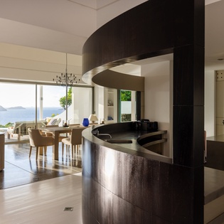 You'll love preparing meals in this stunning curved kitchen while enjoying breathtaking mountain views through floor-to-ceiling windows.