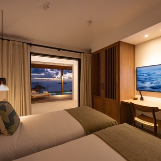 Your serene twin bedroom offers ocean views and modern comfort, with warm wood accents creating the perfect peaceful retreat.