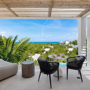 Your private terrace frames breathtaking turquoise waters and tropical palms, perfect for morning coffee or sunset cocktails overlooking paradise.