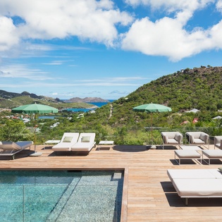 Luxurious infinity pool deck with panoramic ocean and hillside views creates the perfect setting for your Caribbean retreat.