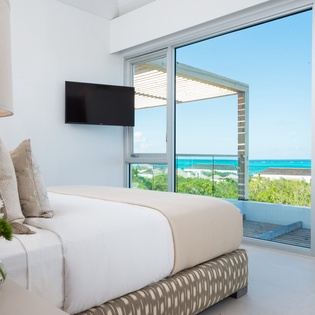 Wake up to stunning turquoise waters from your serene bedroom, where crisp linens and ocean breezes create your perfect island retreat.