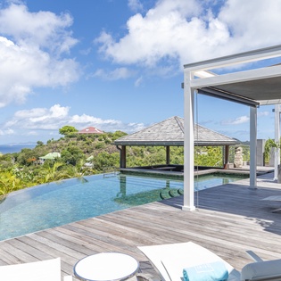 Immerse yourself in tropical luxury with a stunning infinity pool overlooking lush hills and the sparkling sea—your private oasis awaits.