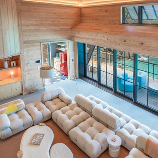 Sink into plush comfort in your modern living room, where warm wood meets contemporary design and floor-to-ceiling windows reveal stunning pool views.