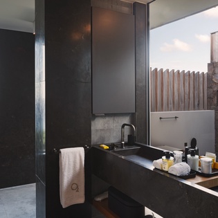 Unwind in your sleek black stone bathroom with stunning ocean views and luxury spa amenities thoughtfully arranged.
