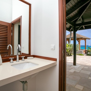 This elegant bathroom opens directly onto the oceanfront patio, letting you freshen up with stunning turquoise views and gentle sea breezes just beyond the door.
