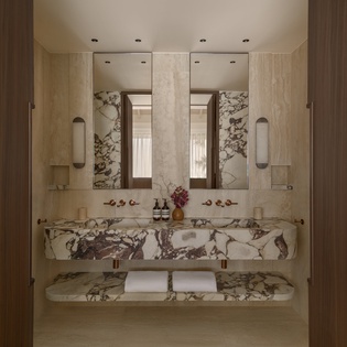 Stunning marble vanity with dual sinks awaits your morning routine, complemented by elegant mirrors and warm lighting.