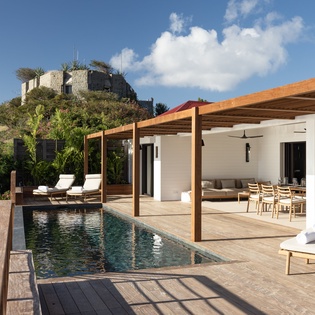 Modern villa with private pool and covered terrace overlooking lush tropical landscape.