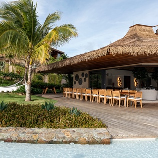 Tropical luxury awaits with thatched-roof dining pavilion, pristine pool, and swaying palms creating your perfect island escape.