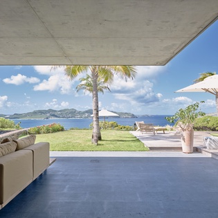 Relax in this stunning open-air living space where ocean breezes flow freely through your tropical retreat, framing endless sea views.