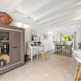 Your bright open-plan kitchen and dining space welcomes you with whitewashed beams, cheerful artwork, and garden views through large windows.