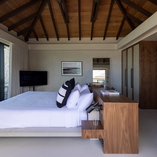Wake up to stunning ocean views in your beautifully appointed bedroom, where warm wood beams and modern design create the perfect sanctuary for rest.
