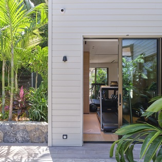 Modern tropical entrance surrounded by lush palms and vibrant greenery creates your private paradise retreat.