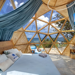 Wake to panoramic views in a light-filled geodesic dome where sky meets sea. Floor-to-ceiling windows frame nature's grandeur, while modern comforts meet unique design—your coastal retreat awaits.