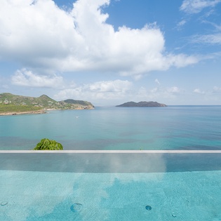 Infinity pool seamlessly blends with turquoise Caribbean waters and tropical islands beyond.