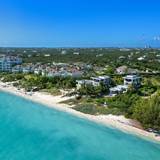 Stunning aerial view of beachfront properties nestled between turquoise waters and lush tropical landscape.