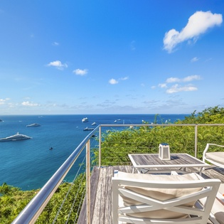 Stunning oceanfront terrace with panoramic sea views and luxury yachts dotting the azure waters below.