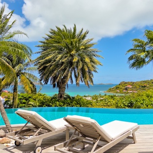Stretch out on your private sun lounger beside the infinity pool, where turquoise waters blend seamlessly with ocean views and swaying palms frame your tropical escape.