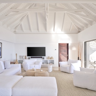 Your bright living space features dramatic white beams, plush seating, and seamless terrace access with mountain views.